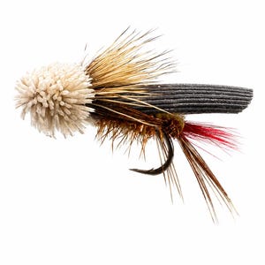 May include: A fishing fly lure featuring a rounded cream-colored foam head, a dark grey ribbed foam body, and brown hackle feathers. The lure includes a sharp metal hook and a small tuft of bright red fibers extending from the rear section.