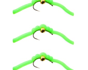 May include: Three green and gold fly fishing lures with a curved body and a bead at the head.