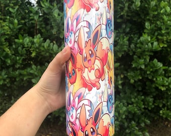 May include: A stainless steel tumbler with a colorful print of cartoon Eevee characters. The tumbler has a lid and is approximately 20 ounces in size.