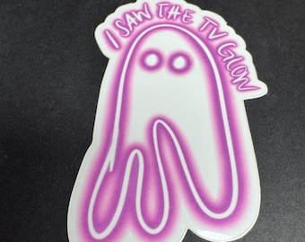 May include: A white ghost sticker with a pink outline. The ghost has two eyes and a mouth. The text "I saw the TV glow" is written around the top of the ghost.