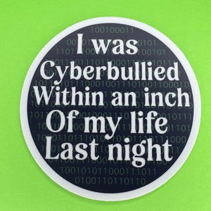 May include: A black and white round sticker with a white border. The sticker has a binary code pattern background with the text "I was cyberbullied within an inch of my life last night".