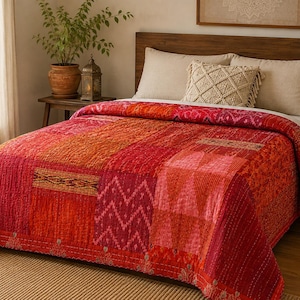 Può includere: Una trapunta patchwork caratterizzata da una vivace tavolozza di colori nei toni del rosso, dell'arancione e del rosa. La trapunta è composta da vari pannelli di tessuto rettangolari con complessi motivi intrecciati, tra cui zigzag e disegni floreali.