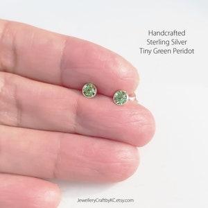 May include: A pair of handcrafted sterling silver stud earrings with tiny green peridot stones.