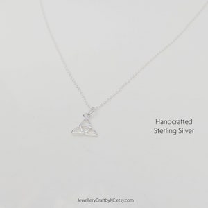May include: A silver necklace with a Celtic knot pendant. The necklace is handcrafted from sterling silver.