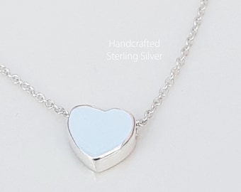 May include: A delicate silver chain necklace with a small, light blue heart pendant. The necklace is handcrafted from sterling silver.