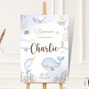 Peut inclure: Panneau de bienvenue de style aquarelle pour un anniversaire. Il présente des illustrations de la vie marine, dont une baleine, un narval et une pieuvre. Le texte indique "Bienvenue À l'Anniversaire de Charlie" et la date.