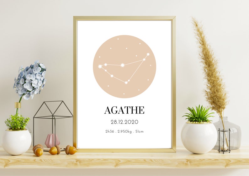 May include: A framed print with a gold border features a Capricorn constellation illustration in white on a peach-colored circle. The name "AGATHE" is below, along with the date, time, weight, and height.