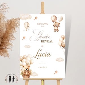 May include: A white sign on an easel with the words "Gender Reveal de Lucia" in elegant script, surrounded by watercolor illustrations of teddy bears, balloons, clouds, and stars. The date "6 Ao&ucirc;t 2024" is also displayed.