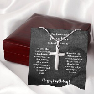 K&ouml;nnte beinhalten: Eine silberne Kreuzkette in einer schwarzen Geschenkbox mit einer Karte, auf der steht "An einen gutaussehenden jungen Mann zu seinem 21. Geburtstag". Die Karte enth&auml;lt eine Botschaft, die lautet: "Zu deinem 21. Geburtstag, stehe stolz und gerade da, wo du auf deiner Lebensreise bist. Feiere die vielen Wege, auf denen du kl&uuml;ger und st&auml;rker im Geiste geworden bist. Wisse, dass dein Leben eine besondere Bedeutung hat und dass der Sinn dieses Tages darin besteht, die einzigartige Person zu ehren, die du geworden bist. Alles Gute zum Geburtstag!"