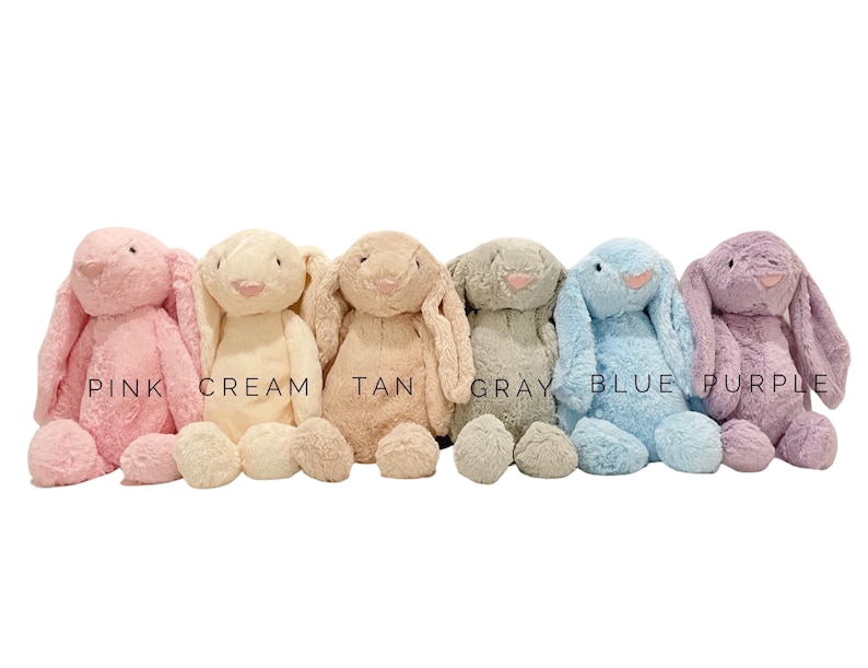 May include: Six plush bunny toys in different colors: pink, cream, tan, gray, blue, and purple. The bunnies are all sitting with their ears up and their eyes closed.