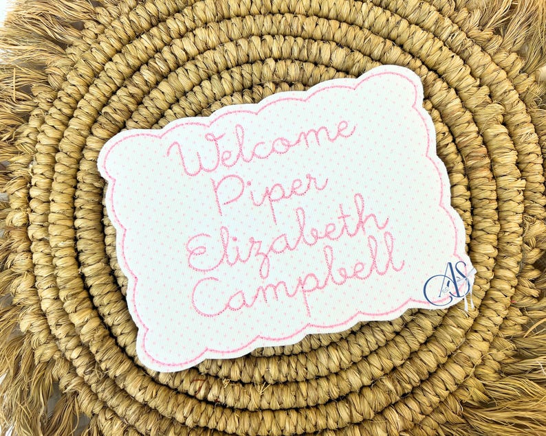 Puede incluir: Bienvenido Piper Elizabeth Campbell, un letrero de bienvenida bordado en rosa con fondo blanco y lunares rosas.