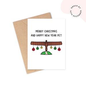 May include: A Christmas card featuring a brown angel illustration with the text "MERRY CHRISTMAS AND HAPPY NEW YEAR PET". The card has red, green, and yellow baubles. It is accompanied by a brown envelope.