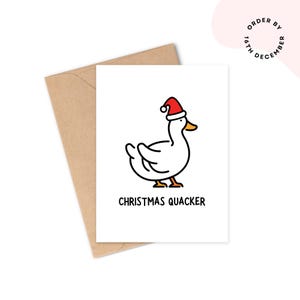 May include: A white Christmas card featuring a cartoon duck wearing a red Santa hat. The card has the text "CHRISTMAS QUACKER". The card is placed inside a brown envelope.