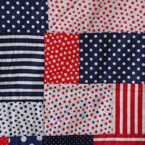 Puede incluir: Una colcha de retazos con un esquema de color rojo, blanco y azul. La colcha est&aacute; hecha de diferentes telas con varios patrones, incluyendo estrellas, rayas, lunares y paisley.