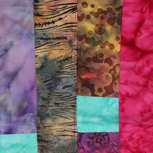 K&ouml;nnte beinhalten: Ein Patchwork-Deckenst&uuml;ck mit verschiedenen Farben und Mustern, darunter Gr&uuml;n, Lila, Braun, Rosa und T&uuml;rkis. Die Decke besteht aus verschiedenen Stoffen, die zusammengen&auml;ht wurden, um ein einzigartiges Design zu schaffen.