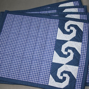 Könnte beinhalten: Satz mit sechs blauen und weißen karierten Tischsets mit einem blauen und weißen Spiralmuster am Rand.