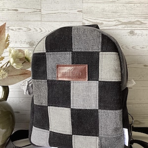 May include: Black and gray checkered backpack with a brown leather patch that says "Hollister Co."