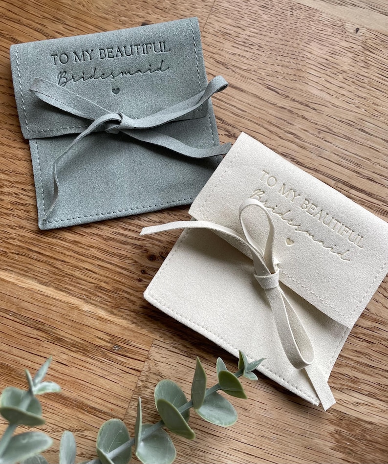 May include: Two small, fabric gift bags with a satin ribbon tie. The bags are light gray and white and have the text "To my beautiful bridesmaid" embossed on the front.
