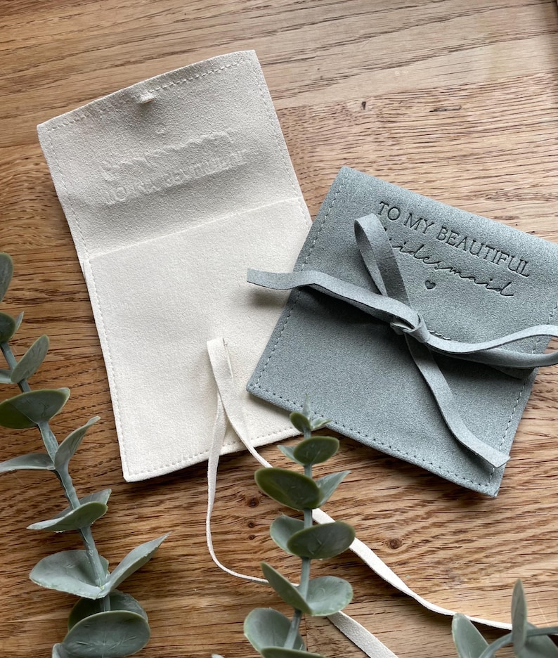 May include: Two small, fabric gift bags. One is white with a subtle embossed design and the other is light blue with the text "To my beautiful bridesmaid" in black.