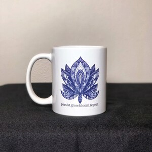 Peut inclure: Une tasse en c&eacute;ramique blanche avec un motif de mandala bleu et blanc et le texte "persist.grow.bloom.repeat."