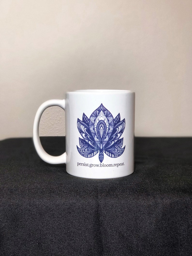 Peut inclure: Une tasse en c&eacute;ramique blanche avec un motif de mandala bleu et blanc et le texte "persist.grow.bloom.repeat."