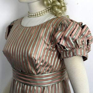 May include: A pink and green striped dress with a fitted bodice and short puffed sleeves. The dress has a simple neckline and a narrow belt.
