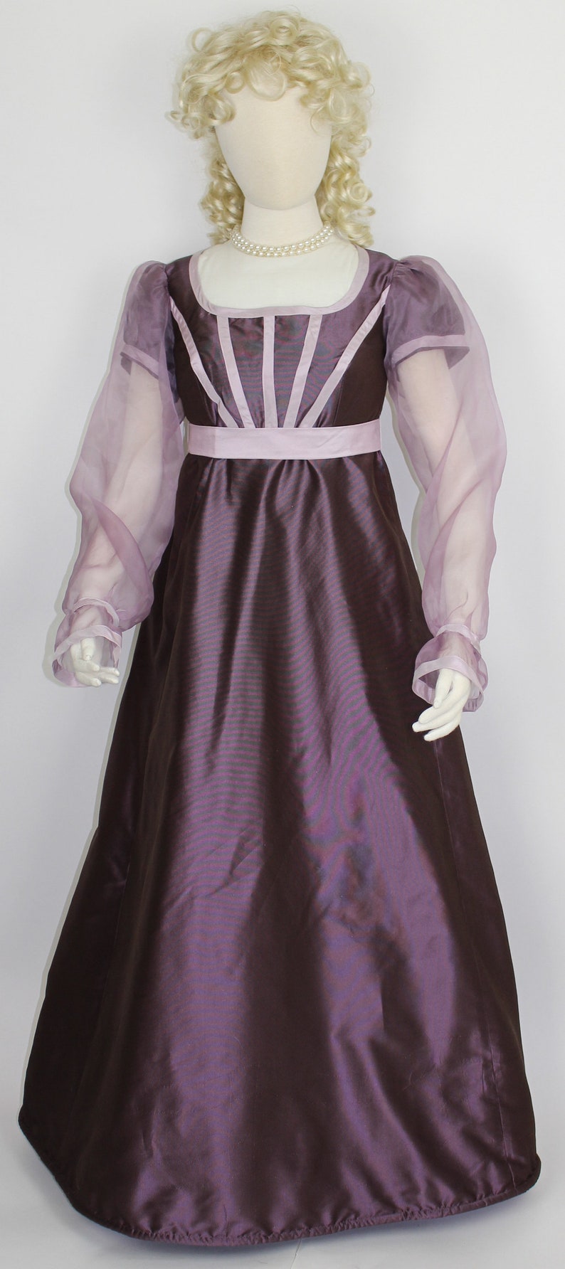 May include: A purple and pink dress with sheer sleeves and a fitted bodice. The dress has a simple, elegant design.