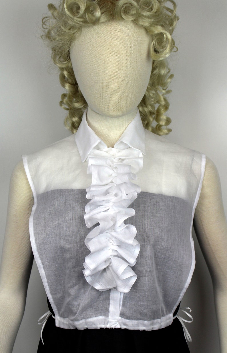 May include: A white sheer blouse with a ruffled collar and a gathered waist. The blouse is sleeveless and has a black undershirt.