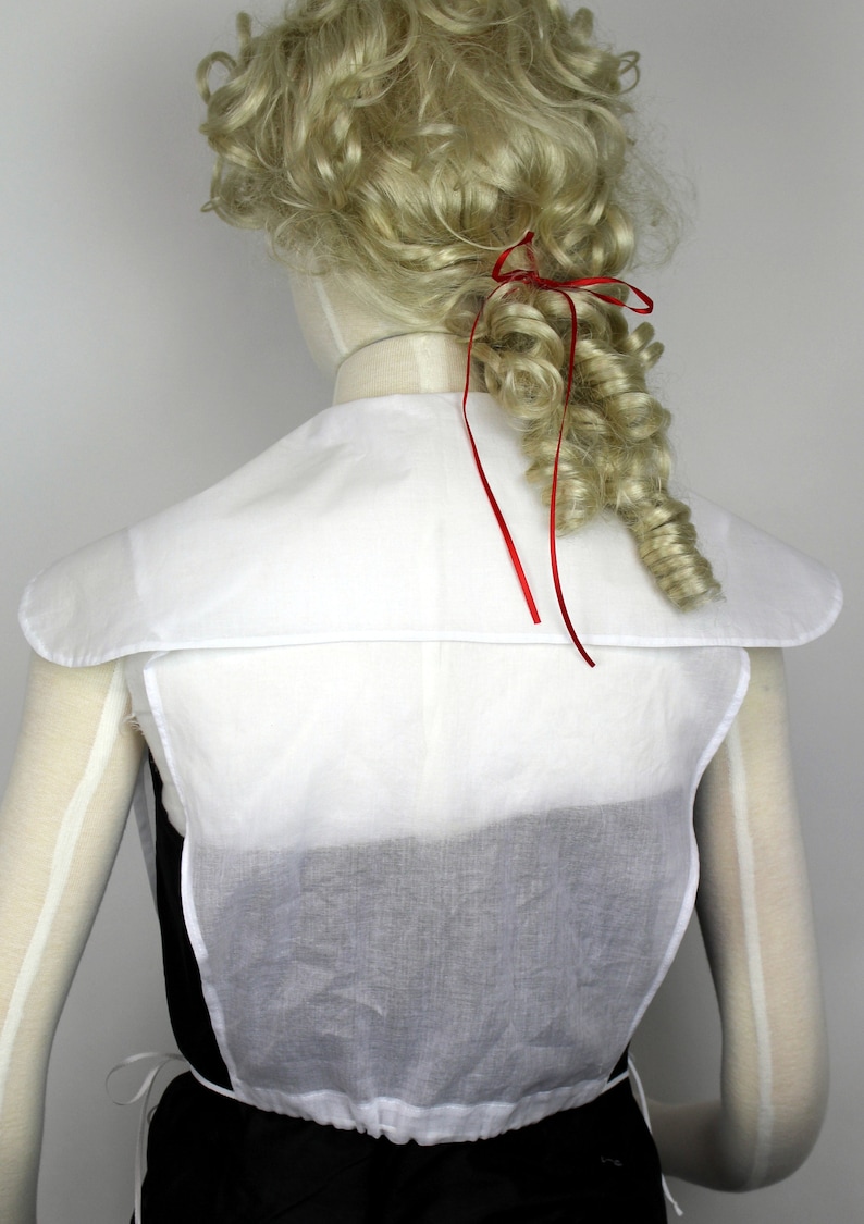 May include: White cotton blouse with a wide, rounded collar and a gathered waist. The blouse is sleeveless and has a simple, elegant design.