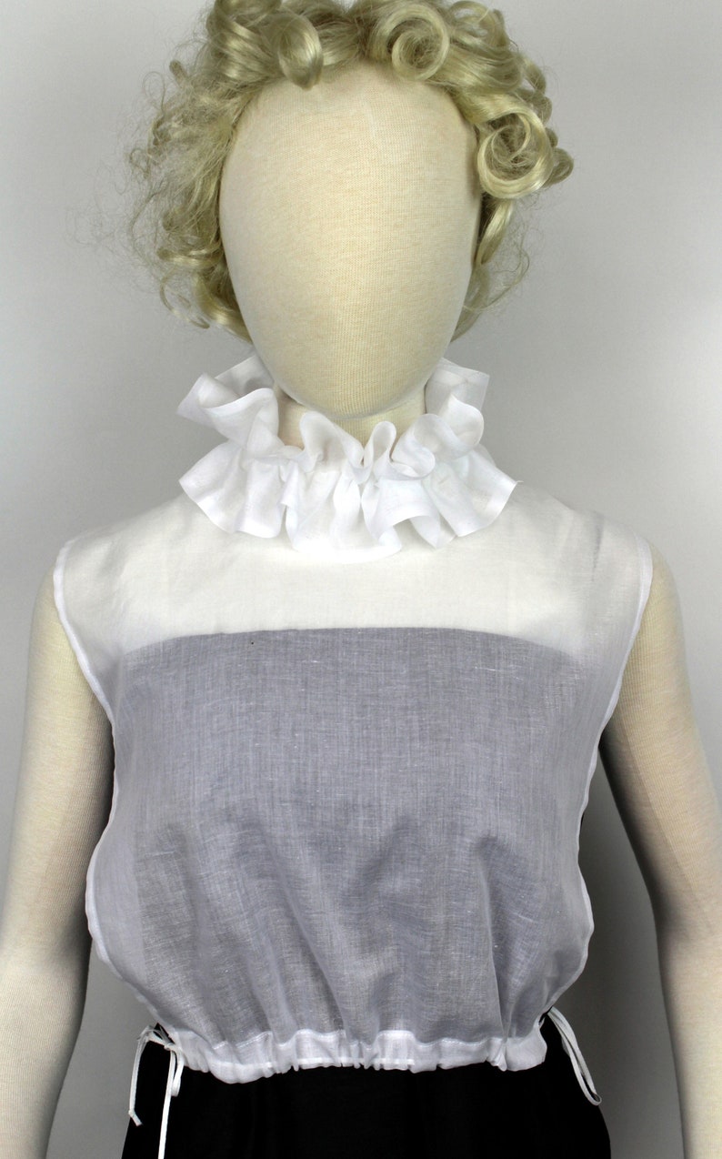 May include: White ruffled collar with a white sleeveless top with a gathered bottom.