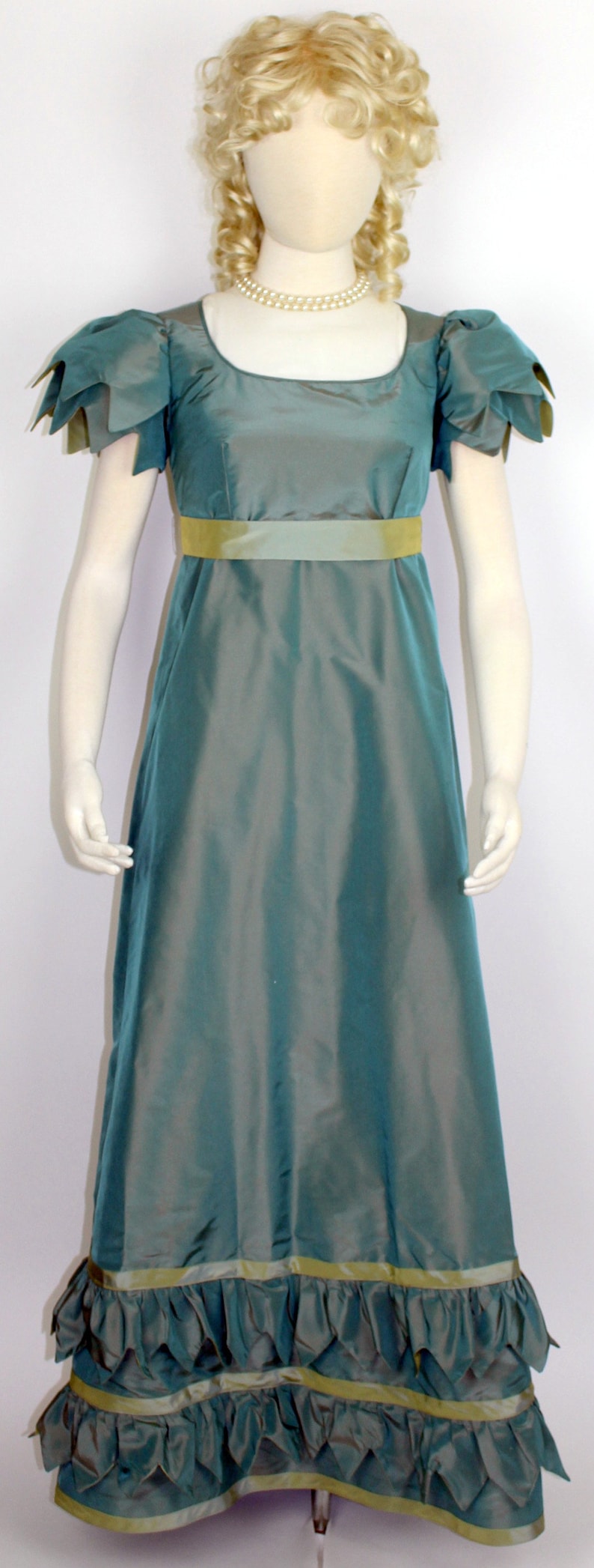 May include: A teal blue dress with a yellow sash and ruffles at the hem. The dress has short sleeves and a fitted bodice.