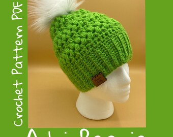 May include: A vibrant green Adri Beanie crochet hat with a white faux fur pom-pom. The hat is displayed on a white mannequin head. The image includes the words "Crochet Pattern PDF" and "Adri Beanie".