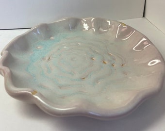 May include: A white ceramic dish with a scalloped edge and a light blue and gold swirl design.