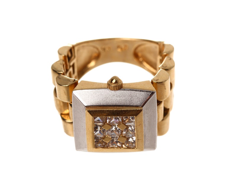 May include: A gold and silver watch ring with a square face and a band of linked gold pieces. The face is set with clear stones.
