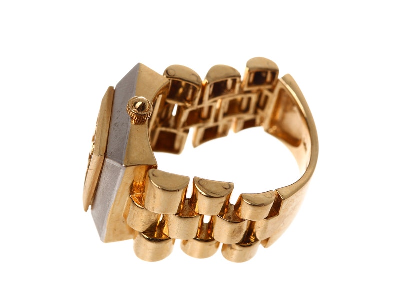 May include: A gold and silver watch ring with a square face and a band that resembles a watch band.