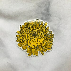May include: A yellow chrysanthemum flower sticker with a detailed illustration of the petals and center.
