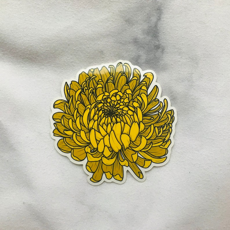 May include: A yellow chrysanthemum flower sticker with a detailed illustration of the petals and center.