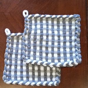 May include: Two gray and white woven pot holders with a white braided edge.