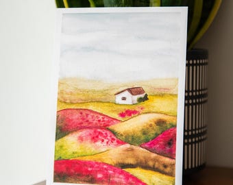May include: A rectangular art print featuring a watercolor landscape painting of a small white house with a brown roof situated in a field of rolling hills colored in vibrant shades of red, yellow, and green under a pale gray sky.
