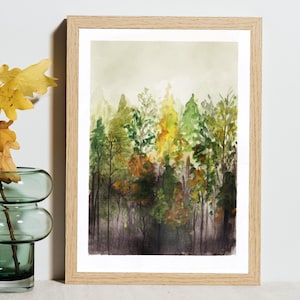 May include: A framed watercolor painting depicting a dense forest scene with varying shades of green, yellow, and brown foliage. The artwork features tall, slender tree trunks and a soft, hazy background, all encased in a light-toned wooden frame.