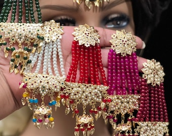 May include: A set of five gold and pearl bridal jewellery pieces with dangling beads. The pieces feature green, white, red, and burgundy beads. Each piece has a gold pendant with a floral design.