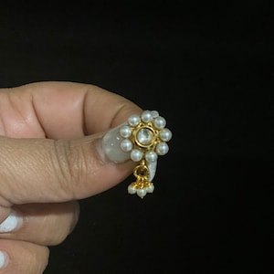 May include: A gold nose ring with a small pearl cluster and a dangling pearl charm.