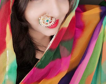May include: A woman wearing a colorful patterned headscarf with a large floral nose ring. The nose ring is gold with white pearls and green gemstones.