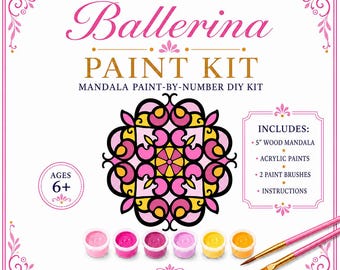 May include: A Ballerina Paint Kit mandala paint-by-number DIY kit by Paperie By Jennifer. Includes a 5-inch wood mandala, 6 acrylic paint pots in shades of pink and yellow, 2 paint brushes, and instructions. The packaging features a pink and yellow mandala graphic and is labeled for ages 6+.