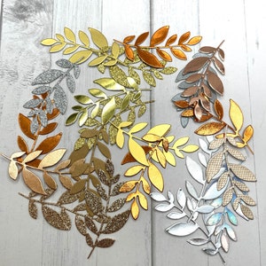 May include: Assortment of gold, silver, and copper leaf sprigs. The leaves are cut from paper and have a glitter finish.