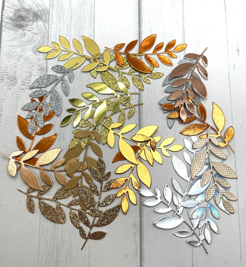 May include: Assortment of gold, silver, and copper leaf sprigs. The leaves are cut from paper and have a glitter finish.
