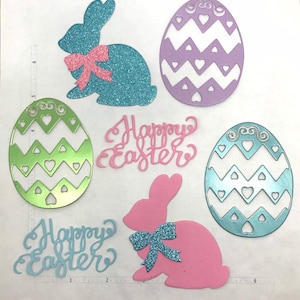 May include: A set of six Easter-themed paper cutouts. The set includes two blue and pink bunnies with glitter bows, two green and blue eggs with a chevron pattern, and two pink and white "Happy Easter" signs.