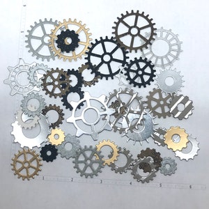 May include: A collection of decorative metal gears in various sizes and patterns. The gears are made of silver, gold, and black metal and have a steampunk aesthetic.