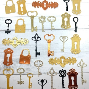 May include: Assortment of gold, copper, and black metal keyhole and key shapes. The keyhole shapes are in various styles, including ornate and simple. The keys are also in various styles, including ornate, simple, and with glitter.