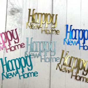 May include: Six different colored paper cutouts that say "Happy New Home". The cutouts are in pink, blue, gold, teal, and light blue.
